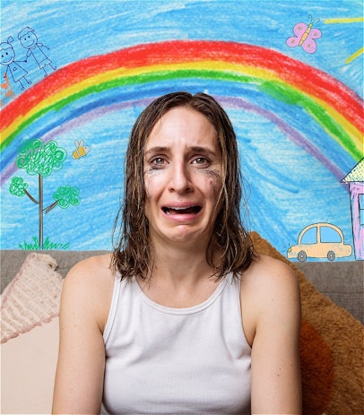 A brown haired woman crying with black mascara down her face. A background of a blue sky and rainbow like a kids drawing.