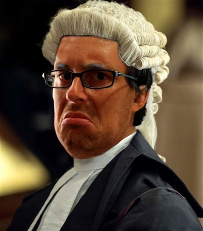 Kieran Bullock in character as Judge Winston, wearing black judge's robes, a traditional British judge's wig, and a stern expression. He is ready to dispense justice!