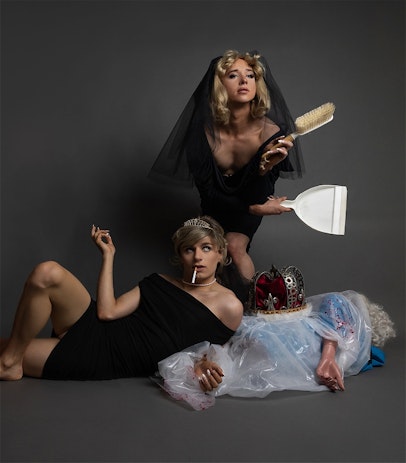 Two divas posing in the illusion of Princess Diana and Queen Consort Head Hoe Camilla Parker Bowles perched seductively over the corpse of Queen Elizabeth II