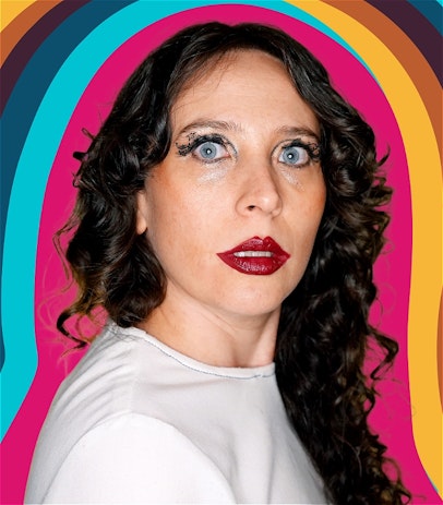 White woman wearing white with brown curly hair, blue eyes and overdrawn red lips looks over her shoulder at something in the distance with wonder and a tiny bit of fear. Block colours in a vaguely 70s palette trail her image.